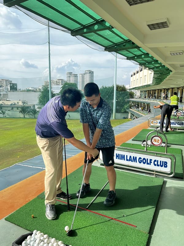 HLV đang sửa tư thế đánh golf chuẩn cho học viên